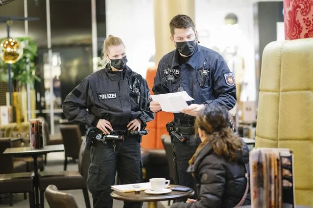 Police officers check the vaccination certificates of guests in a restaurant in Hannover, Germany, Monday, November 29, 2021. On behalf of the local authorities, the police are starting to patrol restaurants and other catering establishments in order to check the measures to battle the spread of the coronavirus. (Photo by Ole Spata/dpa via AP Photo)