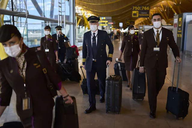 Flight crew members wearing face masks to prevent the spread of coronavirus walk along the Adolfo Suarez-Barajas international airport in Madrid, Spain, Thursday, December 2, 2021. The coronavirus's omicron variant kept a jittery world off-kilter as reports of infections linked to the mutant strain cropped up in more parts of the globe. (Photo by Manu Fernandez/AP Photo)