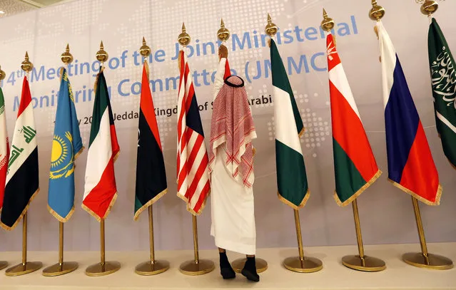 A Saudi worker adjusts flags of participating countries before a meeting of energy ministers from OPEC and its allies to discuss prices and production cuts, in Jiddah, Saudi Arabia, Sunday, May 19, 2019. The meeting takes places as tensions flare in the Persian Gulf after the U.S. ordered bombers and an aircraft carrier to the region over an unexplained threat they perceive from Iran, which comes a year after the U.S. unilaterally pulled out of Tehran's nuclear deal with world powers and reimposed sanctions on Iranian oil. (Photo by Amr Nabil/AP Photo)