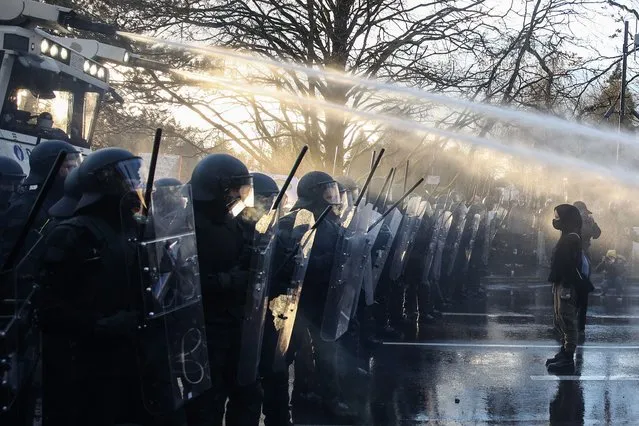 Anti-vaccination demonstrators stand in front of police water canon as they clash with police during a demonstration against government's measures to curb the spread of the Covid-19 in Luxembourg, on December 11, 2021. Several hundred people demonstrated in Luxembourg on December 11, 2021 against anti-Covid measures under close surveillance by the police who used a water cannon and carried out arrests, according to an AFP correspondent. (Photo by Aris Oikonomou/AFP Photo)