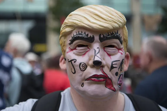 A man wears a Donald Trump mask as protestors gather outside Cardiff Library on the Hayes in Cardiff to protest against a visit by the President of the United States Donald Trump on July 12, 2018 in Cardiff, United Kingdom. (Photo by Matthew Horwood/Getty Images)