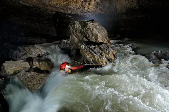 Gravely battling the elements; American speleologist Erin Lynch struggles to pull her way across a raging torrent of white water that relentlessly bombards her with waves and waves of crashing water, wanting to tear her away from her only lifeline and throw her down the main river in Quankou Dong. (Photo by Robbie Shone/Caters News/ImagineChina)