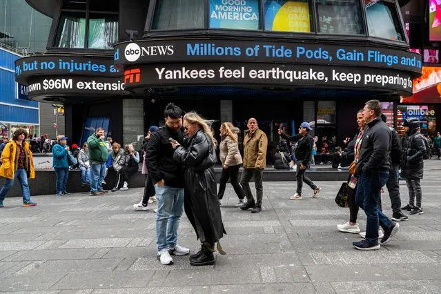 People walk around Times Square as news tickers display news about the earthquake on Friday April 5, 2024 in New York. An earthquake centered between New York and Philadelphia shook skyscrapers and suburbs across the northeastern U.S. for several seconds Friday morning, causing no major damage but startling millions of people in an area unaccustomed to such tremors. (Photo by Brittainy Newman/AP Photo)