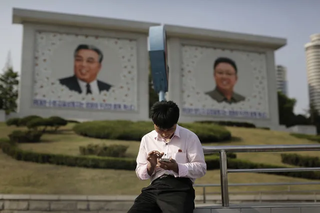 In this May 5, 2015 file photo, a man sits in front of portraits of the late North Korean leaders Kim Il Sung, left, and Kim Jong Il, right, as he uses his smartphone in Pyongyang, North Korea. North Koreans have gained greater access to media and devices like cellphones over Kim Jong Un’s five-year rule, with private citizens of the long-isolated, totalitarian country achieving unprecedented connectedness. But their embrace of a state-controlled network has opened the way to unprecedented government censorship and surveillance. (Photo by Wong Maye-E/AP Photo)