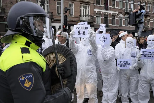 A protestor shows a sign reading “Vrijheid” or “Freedom” to a riot police as thousands of people defied a ban to gather and protest the Dutch government's coronavirus lockdown measures, in Amsterdam, Netherlands, Sunday, January 2, 2022. The municipality of the Dutch capital banned the protest, saying police had indications some demonstrators could be attending “prepared for violence”. (Photo by Peter Dejong/AP Photo)