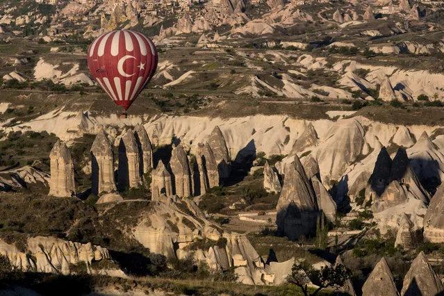 A hot air balloon is seen over rock formations on April 18, 2016 in Nevsehir, Turkey. (Photo by Chris McGrath/Getty Images)