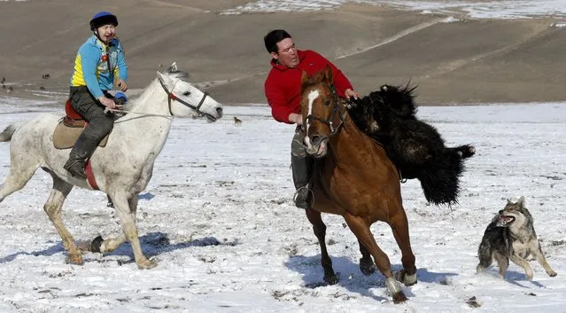 Kyrgyz riders participate in the traditional Central Asian sport “Kok-Boru” (goat dragging), in the village of Besh-Kungei, some 20 kilometers from the capital Bishkek, Kyrgyzstan, 30 January 2022. Kok-boru is a game that is believed to date back from as far as the 10th century when nomadic horse people tribes migrated the regions of Central Asia. Also known by various names in different countries Kok-boru is played by rider teams on horseback grabbing a goat carcass from the ground and try to score by placing it in the opponent's goal. (Photo by Igor Kovalenko/EPA/EFE)