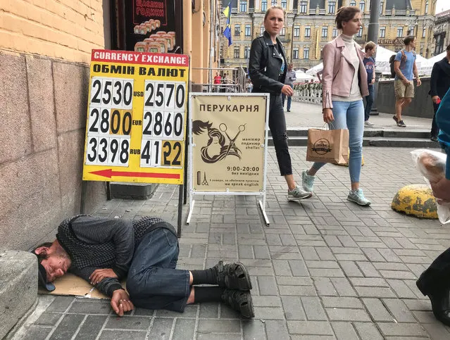 A man sleeps near a display board of a currency exchange office in central Kiev, Ukraine on August 2, 2019. (Photo by Gleb Garanich/Reuters)