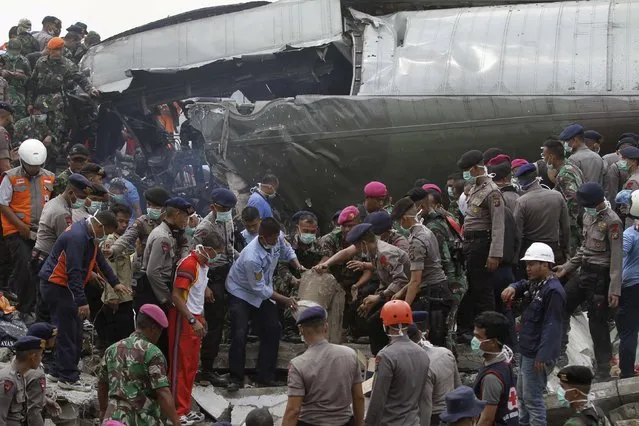 Indonesian security forces and firefighters search through the wreckage of an Indonesian military C-130 Hercules transport plane after it crashed into a residential area in the North Sumatra city of Medan, Indonesia, June 30, 2015. (Photo by Roni Bintang/Reuters)