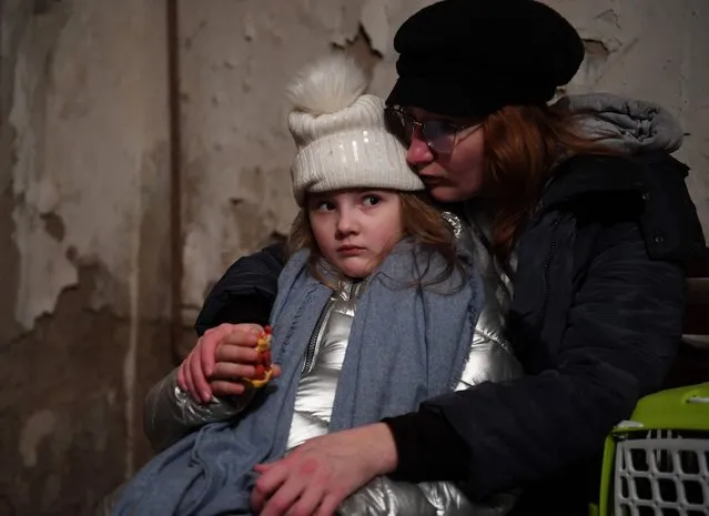 Helga Tarasova comforts her daugther Kira Shapovalova as they wait in an undergound shelter during bombing alert in the Ukrainian capital of Kyiv on February 26, 2022. Ukrainian soldiers beat back a Russian attack in the capital Kyiv only hours after President Volodymyr Zelensky warns Moscow would attempt to take the city before dawn. (Photo by Daniel Leal/AFP Photo)