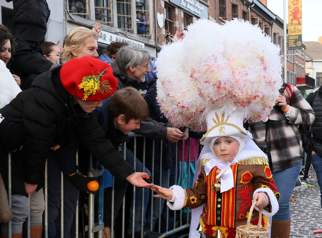 A child wearing a “Gilles” costume holds a basket of oranges while taking part in the Binche carnival, a UNESCO World Heritage event, in Binche, Belgium on February 21, 2023. (Photo by Yves Herman/Reuters)