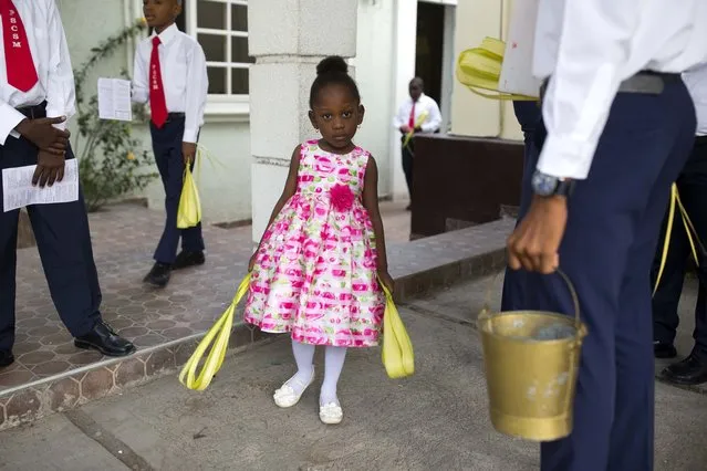 In this Sunday, April 9, 2017 photo, a girl holds palm fronds before the start of a Palm Sunday Mass in Port-au-Prince, Haiti. Palm Sunday commemorates Jesus Christ's triumphant entrance into Jerusalem only to be followed later by his death on a wooden cross. (Photo by Dieu Nalio Chery/AP Photo)