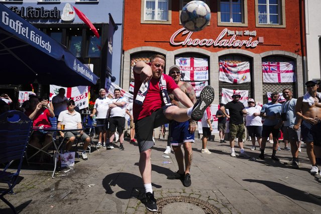 An English soccer fan kicks a ball as he gather with other fans ahead of a Group C match between England and Slovenia at the Euro 2024 soccer tournament in the city center in Cologne, Germany, Tuesday, June 25, 2024. (Photo by Markus Schreiber/AP Photo)