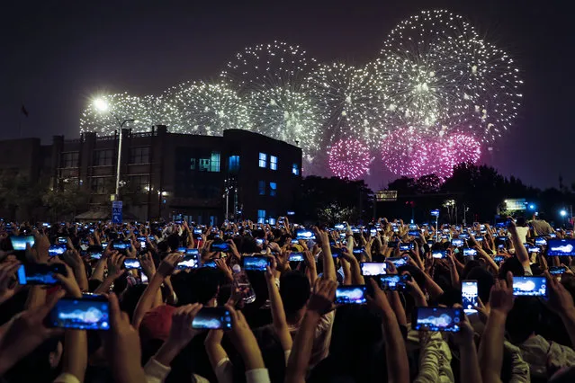 People use smartphones to film fireworks exploding at Tiananmen Square as part of a gala evening commemorating the 70th anniversary of the founding of Communist China light up the sky in Beijing, Tuesday, October 1, 2019. China's Communist Party marked 70 years in power with a military parade Tuesday that showcased the country's global ambitions while police in Hong Kong fought protesters in a reminder of strains at home. (Photo by Andy Wong/AP Photo)