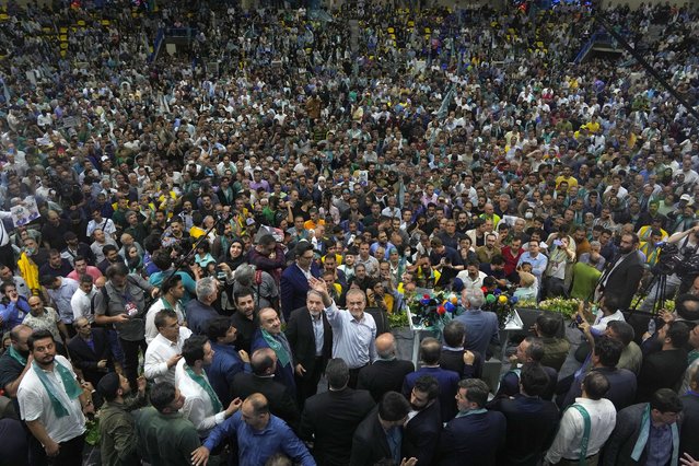 Reformist candidate for Iran's June 28, presidential election Masoud Pezeshkian, bottom center, waves to media in his campaign meeting in Tehran, Iran, Sunday, June 23, 2024. Iran's Guardian Council has approved six candidates to run in the election to replace the late President Ebrahim Raisi, who was killed in a helicopter crash with seven other officials in May. (Photo by Vahid Salemi/AP Photo)