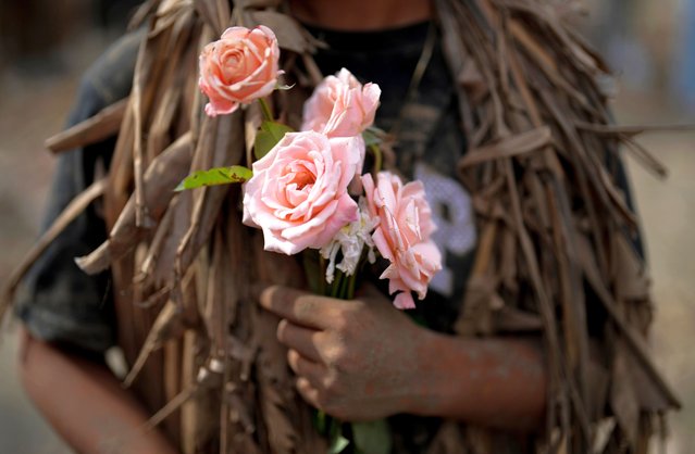 A devout Catholics stands with roses at the church of Saint John the Baptist during the mud festival at Bibiclat, Nueva Ecija province, northern Philippines, Monday, June 24, 2024. (Photo by Aaron Favila/AP Photo)