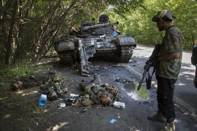 A pro-Russian fighter, right, stands next to bodies of crew members of destroyed Ukrainian tank in the northern outskirts of city of Donetsk, eastern Ukraine, July 22, 2014.A peace agreement for eastern Ukraine has remained stalled for years, but it has come into the spotlight again amid a Russian military buildup near Ukraine that has fueled invasion fears. On Thursday, Feb. 10, 2022 presidential advisers from Russia, Ukraine, France and Germany are set to meet in Berlin to discuss ways of implementing the deal that was signed in the Belarusian capital of Minsk in 2015. (Photo by Dmitry Lovetsky/AP Photo/File)
