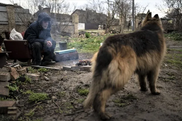 Gregoriev warms himself with a fire in the yard of his house in Bucha, in the outskirts of Kyiv, Ukraine, Saturday, April 9, 2022, which was badly damaged in the war caused by Russia's invasion. (Photo by Rodrigo Abd/AP Photo)