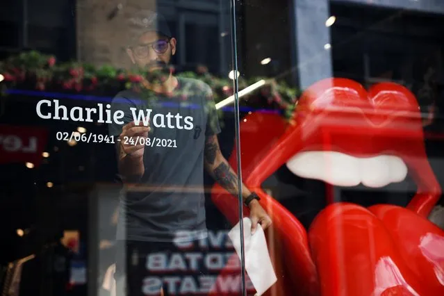An employee of RS No. 9 Carnaby, a Rolling Stones branded shop, places a tribute to Rolling Stones drummer Charlie Watts on the window of the store following the death of the drummer, in London, Britain, August 25 2021. (Photo by Henry Nicholls/Reuters)