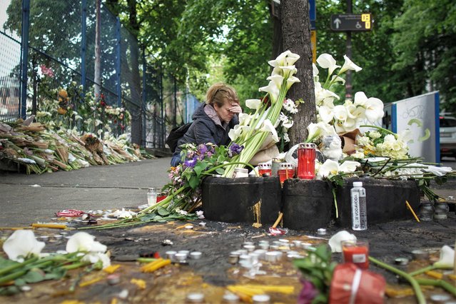 A woman reacts as she sits in front of flowers brought by people for the victims outside the Vladislav Ribnikar elementary school in the capital Belgrade, on May 4, 2023, a day after a 13-year-old suspect shot dead eight fellow students and a security guard after allegedly drawing up a kill list. The tragedy has left the Balkan nation reeling. Gun violence at schools is extremely rare in Serbia and the country's president called Wednesday's shooting “one of the most difficult days” in recent history. (Photo by Oliver Bunic/AFP Photo)