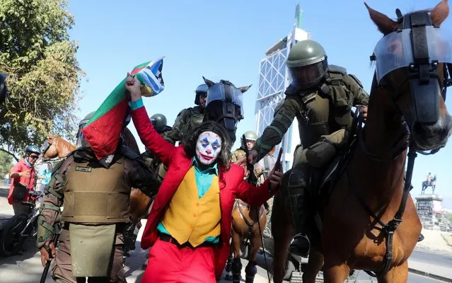 Members of the security forces hold a man dressed as a clown during a protest against Chile's government in Santiago, Chile on December 27, 2019. (Photo by Ivan Alvarado/Reuters)
