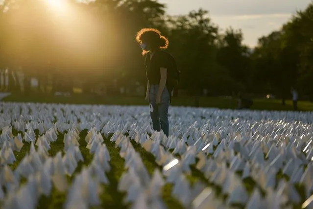 Zoe Nassimoff, of Argentina, looks at white flags that are part of artist Suzanne Brennan Firstenberg's temporary art installation, “In America: Remember”, in remembrance of Americans who have died of COVID-19, on the National Mall in Washington, Friday, September 17, 2021. Nassimoff's grandparent who lived in Florida died from COVID-19. (Photo by Brynn Anderson/AP Photo)