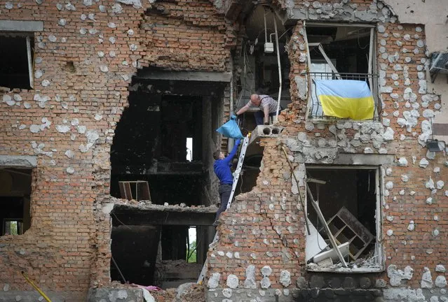 Residents take out their belongings from their house ruined by the Russian shelling in Irpin close to Kyiv, Ukraine, Saturday, May 21, 2022. (Photo by Efrem Lukatsky/AP Photo)