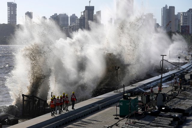 Coastal road workers walk as waves hit the city's waterfront during high tide in the Arabian Sea at Marine Drive as authorities make arrangements to tackle the approach of Cyclone Biparjoy in Mumbai, India, Saturday, June 10, 2023. (Photo by Rajanish Kakade/AP Photo)