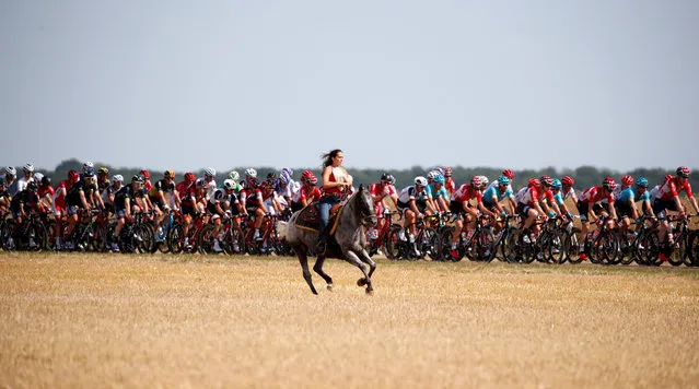 A woman rides a horse along the pack of riders passing through during the 216-kilometer Stage 6 Tour de France cycling race from Vesoul to Troyes, France on July 6, 2017. (Photo by Christian Hartmann/Reuters)
