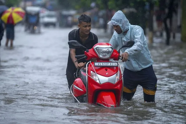 Boys push a scooter past a flooded street during heavy rainfall in Gauhati, India, Thursday, June 16, 2022. (Photo by Anupam Nath/AP Photo)