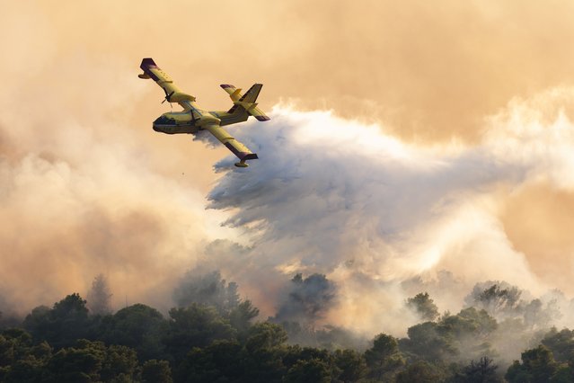 A firefighting plane sprays water to extinguish wildfire at Ciovo island, Croatia, Thursday, July 27, 2023. A large fire is reported on the island of Ciovo, close to Split on the Croatian Adriatic coast. (Photo by Miroslav Lelas/AP Photo)