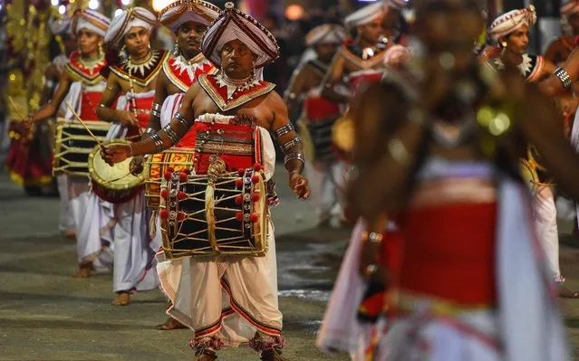 In this photograph taken on January 9, 2020, performers take part in a parade at the annual Perahera festival at the historic Kelaniya Buddhist temple in Kelaniya. Hundreds of devotees and onlookers gathered for the annual elephant pagent, held on the night before the full moon day in January, to commemorate the visit of Lord Buddha to the temple. (Photo by Ishara S. Kodikara/AFP Photo)