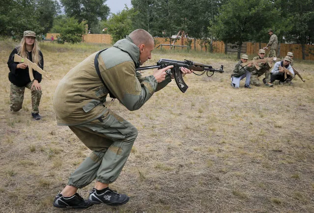 In this photo taken on Friday, July 14, 2017, a trainer at a paramilitary camp for children holds a rifle during exercises outside Kiev, Ukraine. (Photo by Efrem Lukatsky/AP Photo)