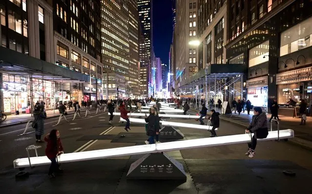 People play on an installation called “Impulse”, twelve glowing seesaws, located on Broadway close to Time Square on January 29, 2020 in New York City. (Photo by Johannes Eisele/AFP Photo)