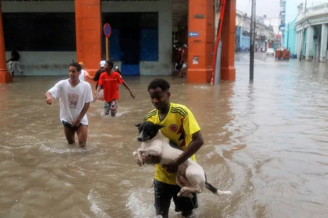 A man carries a dog on a flooded street during heavy rains in Havana, Cuba, June 3, 2022. (Photo by Alexandre Meneghini/Reuters)