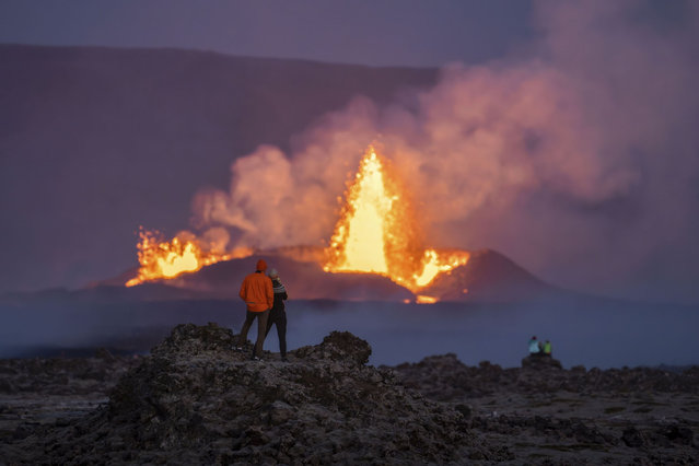 People watch the erupting craters and the lava fountains from the old lava fields around the eruption site on the Reykjanes Peninsula, in Iceland, Wednesday, August 28, 2024. (Photo by Marco di Marco/AP Photo)