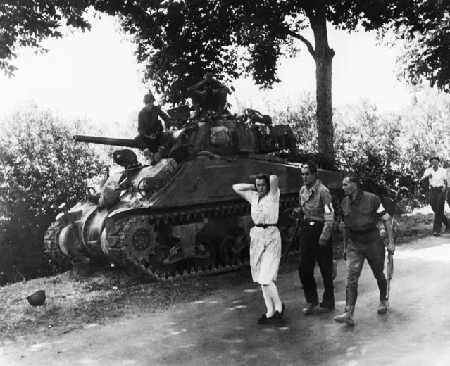 A French woman, accused of being a German sympathizer, is marched along a road past an American heavy tank followed by two armed French partisans on August 19, 1944. She is being taken to Pre en Pail, France, there to be shorn of her hair. (Photo by AP Photo)