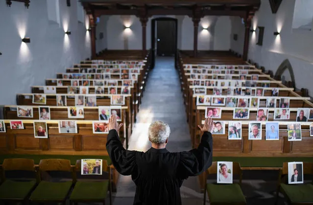 The evangelical pastor Klaus-Martin Pothmann stands in front of photos of believers who were asked to send in pictures to represent them among the pews at the St. Pankratius church in Hamm, western Germany, on April 9, 2020, due to the spread of the novel coronavirus COVID-19. (Photo by Ina Fassbender/AFP Photo)