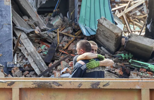 Rescuers react near the body of a killed person who was taken out from the debris of the social and cultural center building which was damaged in the previous day's shelling in the city of Chuhuiv, Ukraine, 26 July 2022. Search operations for people under the rubble in the basements used as shelters continued, the chairman of the Kharkiv Regional State Administration Synegubov said. Kharkiv and surrounding areas have been the target of heavy shelling since February 2022, when Russian troops entered Ukraine starting a conflict that has provoked destruction and a humanitarian crisis. (Photo by Sergey Kozlov/EPA/EFE)