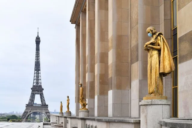 The golden statues of the Trocadero esplanade, in front of the Eiffel Tower, are covered with protective face masks on May 03, 2020 in Various Cities, France. The Coronavirus (COVID-19) pandemic has spread to many countries across the world, claiming over 245,000 lives and infecting over 3.5 million people. (Photo by Pierre Suu/Getty Images)