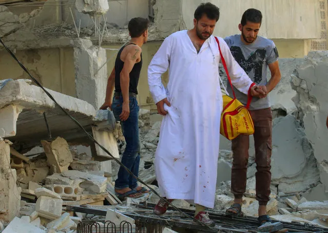 A man with his clothes stained with blood walks on the rubble at a site hit by air strikes in Idlib city, Syria July 20, 2016. (Photo by Ammar Abdullah/Reuters)