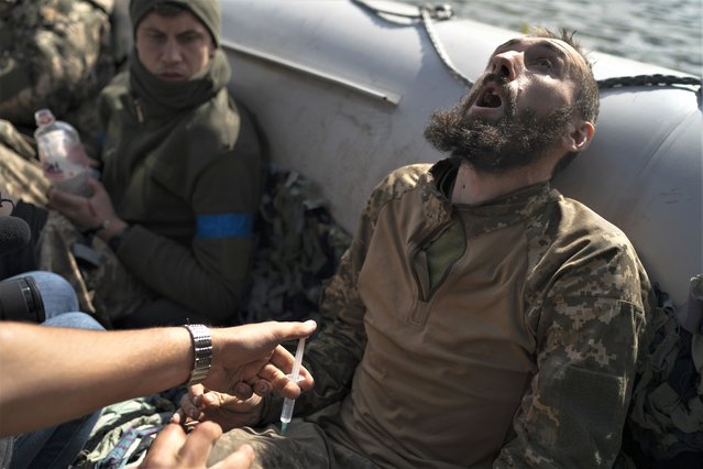 A Ukrainian soldier reacts as he receives an injection during an evacuation of injured soldiers participating in the counteroffensive, in a region near the retaken village of Shchurove, Ukraine, Sunday, September 25, 2022. (Photo by Leo Correa/AP Photo)