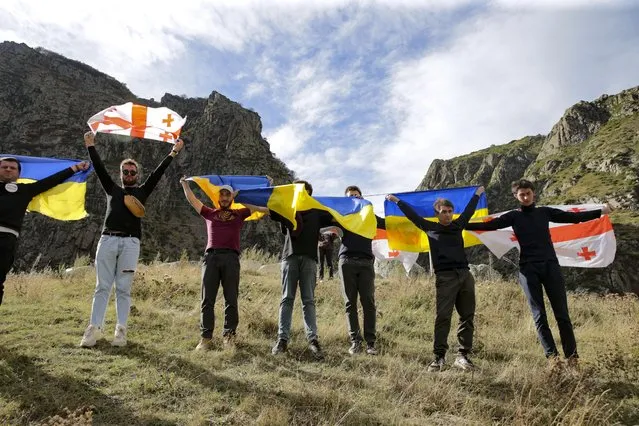 Activists wave Georgian and Ukrainian national flags during an action organized by political party Droa near the border crossing at Verkhny Lars between Georgia and Russia in Georgia, on Wednesday, September 28, 2022. Protesters came from Tbilisi to voice their concerns over the exodus of Russian citizens into Georgia that has increased since Vladimir Putin announced partial mobilization. (Photo by Zurab Tsertsvadze/AP Photo)
