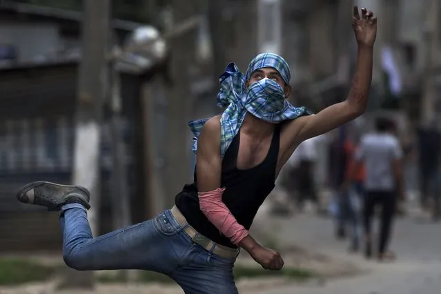 A Kashmiri Muslim protester throws a stone at Indian security personnels during a protest in Srinagar, Indian controlled Kashmir, Tuesday, August 9, 2016. Indian Prime Minister, Narendra Modi, on Tuesday appealed to the people of Indian-controlled Kashmir to shun violence in his first public comments on the region's situation after a month marked by massive anti-India protests and deadly violence. (Photo by Dar Yasin/AP Photo)