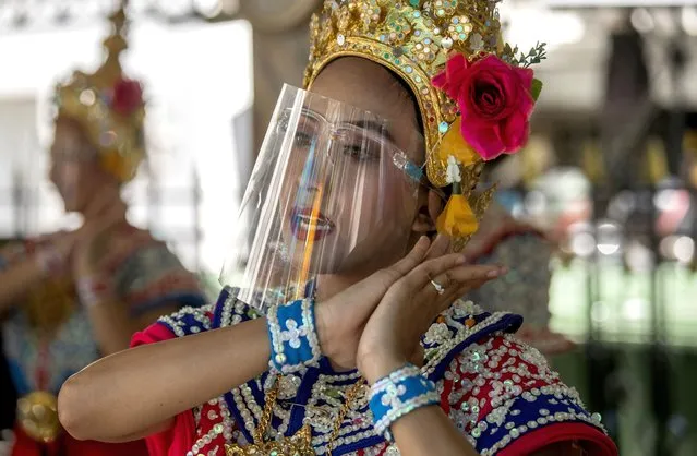 A Thai classical dancer wearing face shield to help curb the spread of the coronavirus performs at the Erawan Shrine in Bangkok, Thailand, Thursday, May 28, 2020. Thai government continues to ease restrictions related to running business in capital Bangkok that were imposed weeks ago to combat the spread of COVID-19. (Photo by Sakchai Lalit/AP Photo)