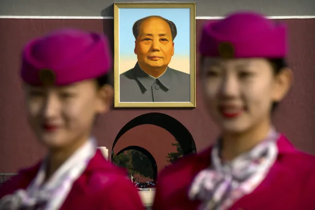 Hospitality staff members pose for a group photo near the large portrait of Mao Zedong on Tiananmen Gate before the closing ceremony of China's 19th Party Congress at the Great Hall of the People in Beijing, Tuesday, October 24, 2017. The ruling Communist Party on Tuesday formally lifted Xi Jinping's status to China's most powerful ruler in decades, setting the stage for the authoritarian leader to tighten his grip over the country while pursuing an increasingly muscular foreign policy and military expansion. (Photo by Mark Schiefelbein/AP Photo)