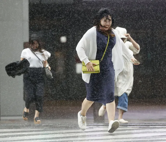 People make their way through the strong wind and rain in Kagoshima, southern Japan, Sunday, September 18, 2022, as a powerful typhoon pounded southern Japan. (Photo by Kyodo News via AP Photo)