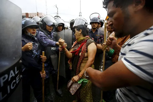 Nepalese riot police try to detain a Hindu activist (C) with torn clothing who argues with the police personnel after being hit by the water canonn during a protest rally demanding Nepal to be declared as a Hindu state in the new constitution, in Kathmandu, Nepal September 14, 2015. (Photo by Navesh Chitrakar/Reuters)
