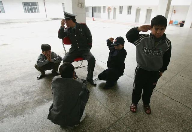 Chinese kids play with a security guard at an assistance center February 23, 2005 in Shenzhen, Guangdong Province, China. (Photo by Cancan Chu/Getty Images)