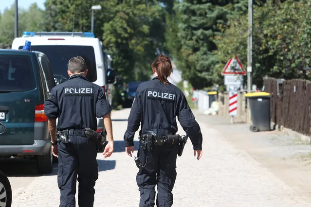 Police officers walk along a road in Reuden, Germany,Thursday August 25,  2016. Three people have been wounded in an armed standoff between police and members of a group that denies the legitimacy of the modern German state in Reuden, eastern Germany. A spokeswoman for police in the eastern state of Saxony-Anhalt says the shootout happened while about 100 police, including a tactical response team, were trying to enforce an eviction order against a 41-year-old “Reich citizen” early Thursday. (Photo by Sebastian Willnow/DPA via AP Photo)